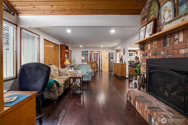 living room with recessed lighting, a brick fireplace, and wood finished floors