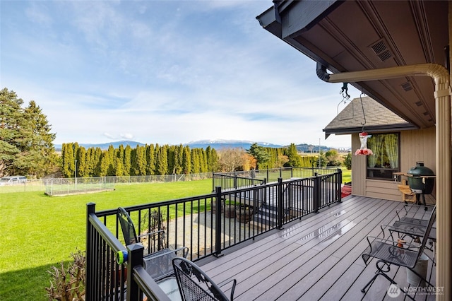 wooden terrace with area for grilling, a lawn, a mountain view, and a fenced backyard