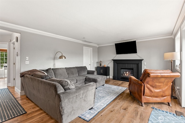 living area featuring light wood finished floors, a tile fireplace, and crown molding