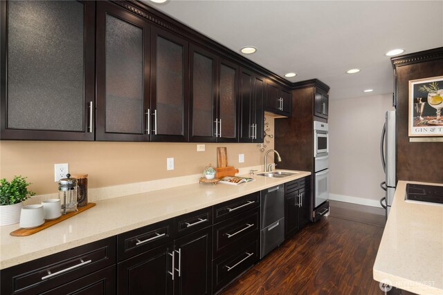 kitchen featuring baseboards, recessed lighting, freestanding refrigerator, a sink, and dark wood-type flooring