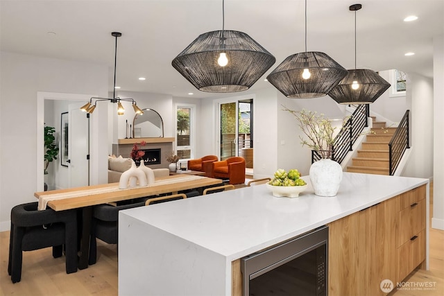 kitchen with light wood-style floors, a kitchen island, modern cabinets, and a fireplace