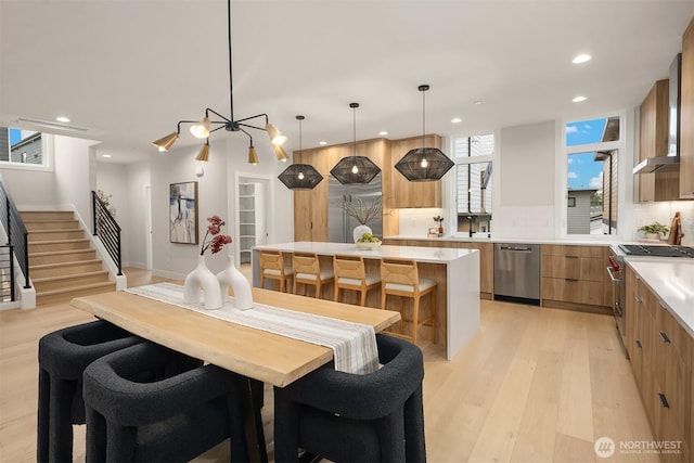 dining space featuring light wood finished floors, recessed lighting, and stairs