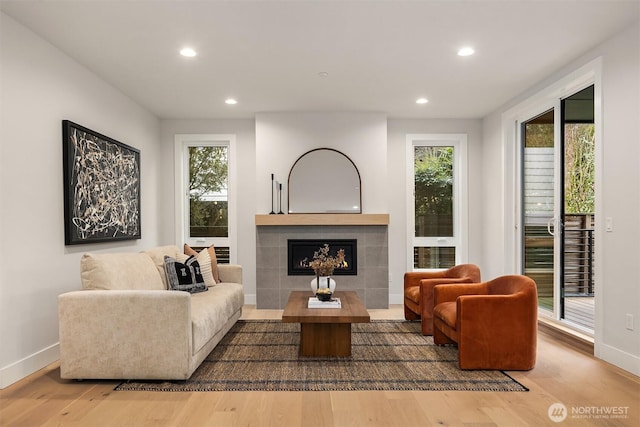 living room featuring a healthy amount of sunlight, a tile fireplace, and wood finished floors