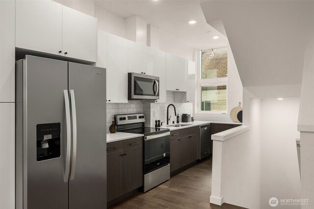 kitchen featuring a sink, light countertops, decorative backsplash, appliances with stainless steel finishes, and dark wood-style flooring