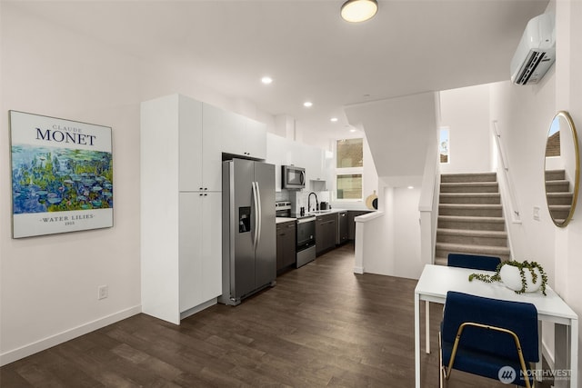 kitchen with a wall mounted AC, stainless steel appliances, light countertops, dark wood-type flooring, and white cabinetry