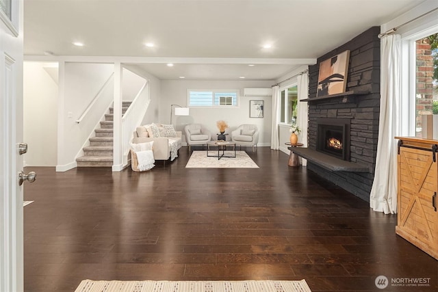 living room featuring a healthy amount of sunlight, a fireplace, stairs, and hardwood / wood-style floors