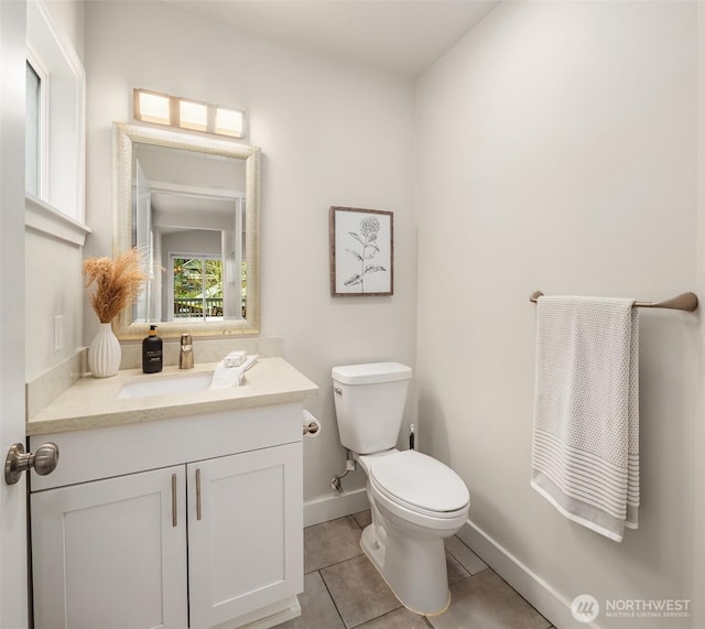 half bathroom featuring tile patterned flooring, toilet, vanity, and baseboards