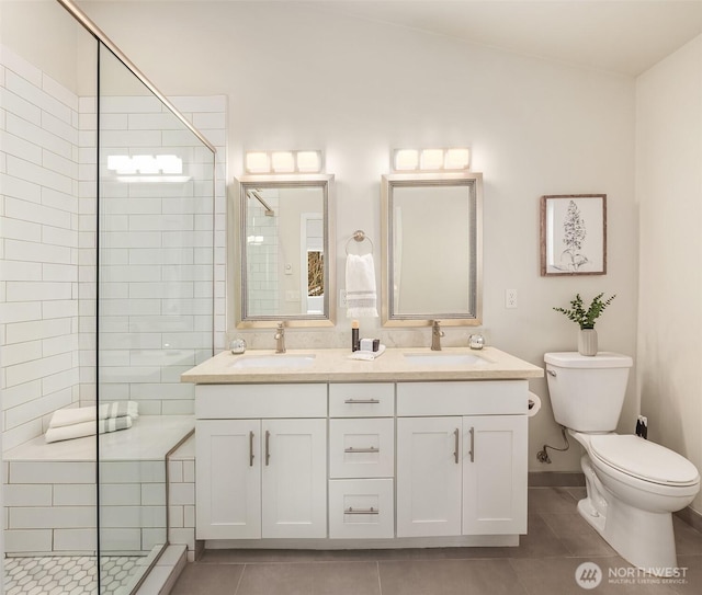 bathroom with a sink, toilet, a tile shower, and tile patterned flooring