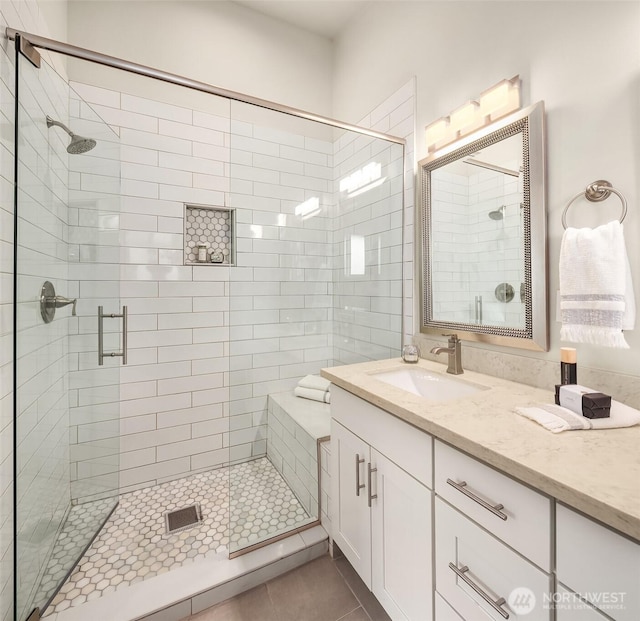 bathroom featuring tile patterned flooring, a stall shower, and vanity