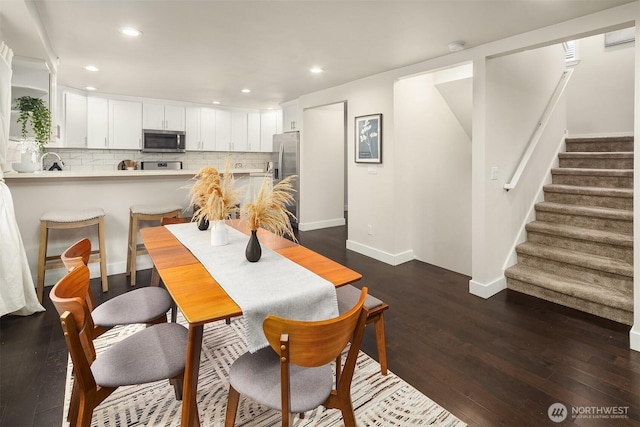 dining space with recessed lighting, baseboards, dark wood-type flooring, and stairs