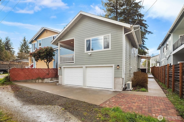 back of house featuring an attached garage, concrete driveway, and fence