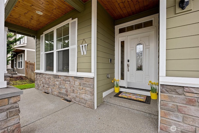 entrance to property featuring a porch, visible vents, and stone siding