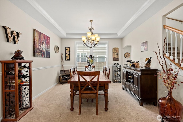 dining space featuring a tray ceiling, stairway, an inviting chandelier, crown molding, and light colored carpet