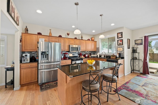 kitchen featuring a healthy amount of sunlight, appliances with stainless steel finishes, a center island, and light wood-type flooring