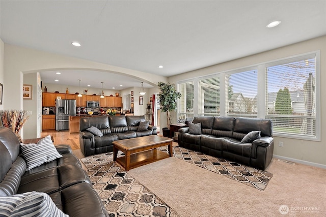 living area with arched walkways, visible vents, recessed lighting, and baseboards