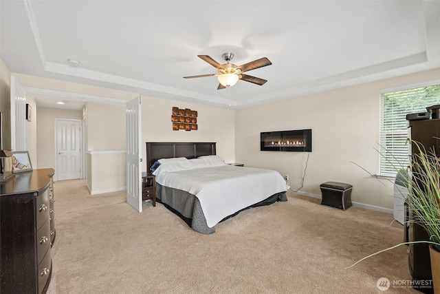 bedroom with a raised ceiling, light colored carpet, and baseboards