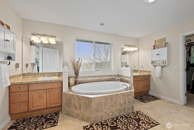 full bathroom with tile patterned floors, a walk in closet, two vanities, a sink, and a bath