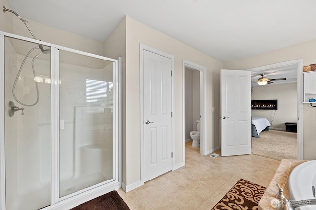 bathroom with a shower stall, toilet, baseboards, and ceiling fan