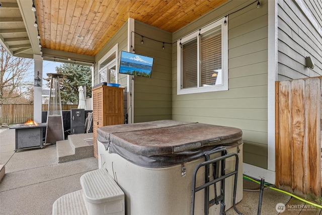 view of patio / terrace with fence, an outdoor fire pit, and a hot tub