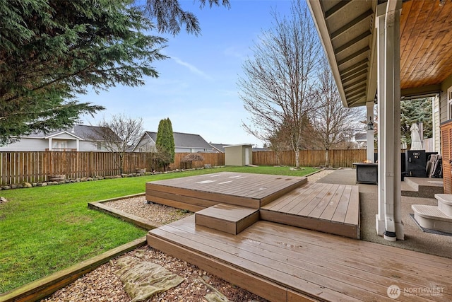 deck featuring a yard, an outdoor structure, a fenced backyard, and a shed