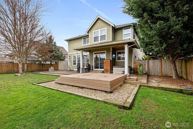 back of house featuring a wooden deck, a lawn, and a fenced backyard