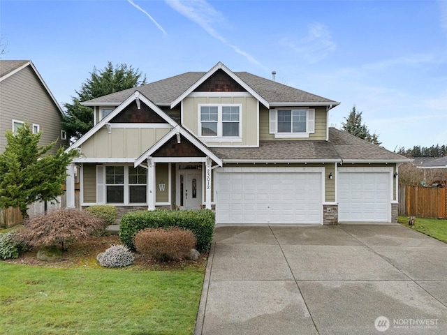 craftsman-style home featuring board and batten siding, a front lawn, fence, a garage, and driveway