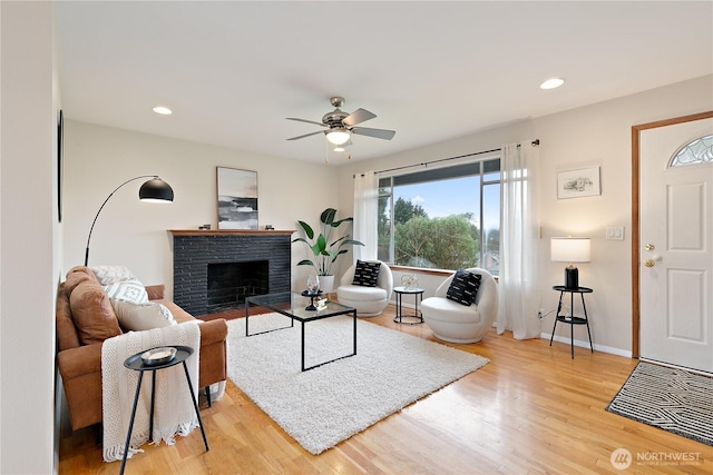 living area with wood finished floors, baseboards, a ceiling fan, a fireplace, and recessed lighting