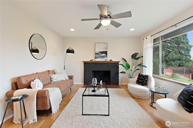 living room featuring recessed lighting, baseboards, a brick fireplace, and light wood finished floors