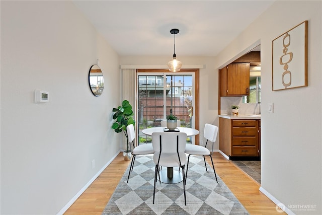 dining space featuring light wood-style flooring and baseboards