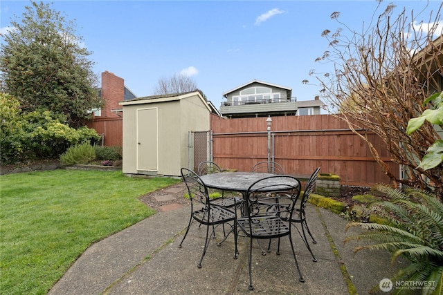 view of patio featuring outdoor dining area, an outbuilding, a storage shed, and fence