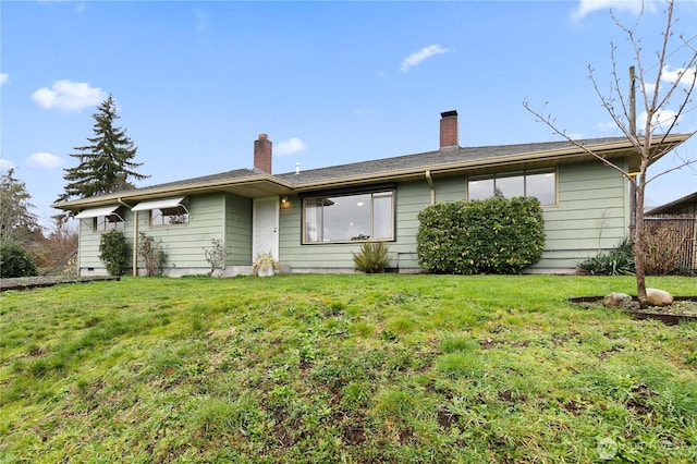 rear view of property with a chimney and a yard