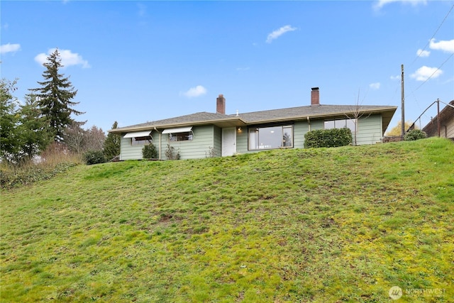 rear view of house with a lawn and a chimney