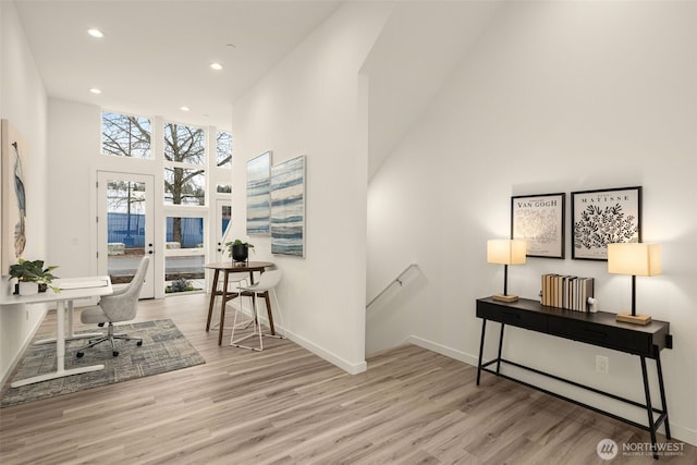 home office with recessed lighting, baseboards, a high ceiling, and wood finished floors