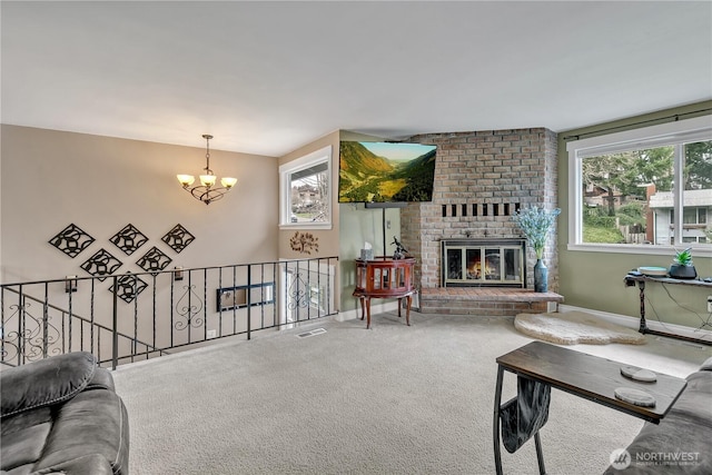 carpeted living area featuring a wealth of natural light, visible vents, a brick fireplace, and a chandelier