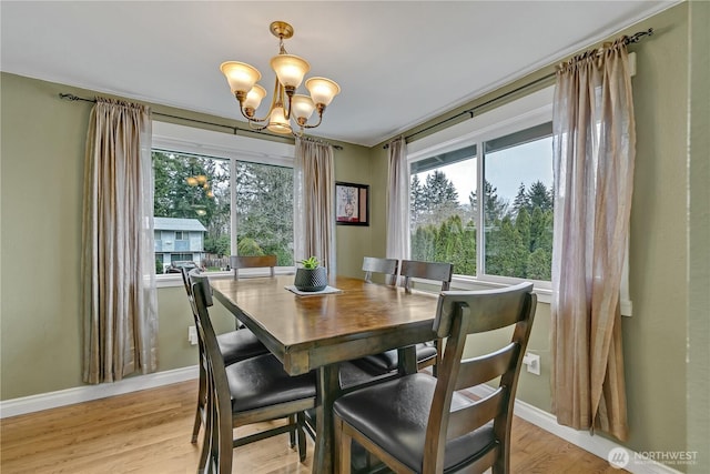 dining room with a chandelier, baseboards, and light wood-style flooring