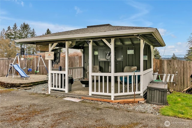 exterior space featuring fence and a shingled roof