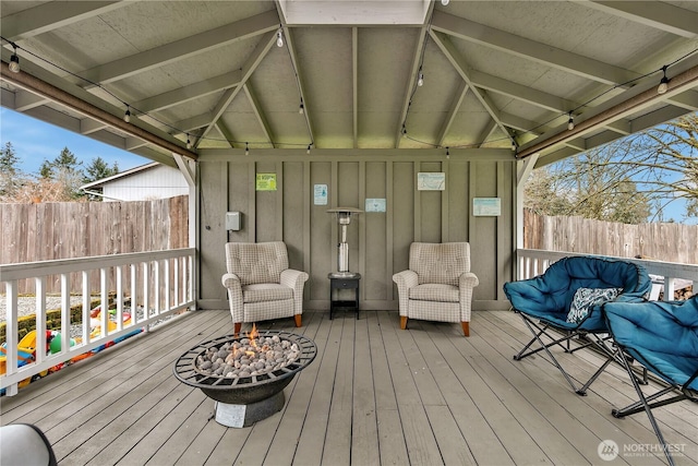 wooden terrace featuring a fire pit and fence