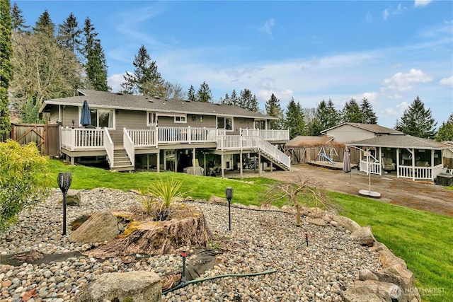 back of house featuring stairway, a lawn, a deck, and fence