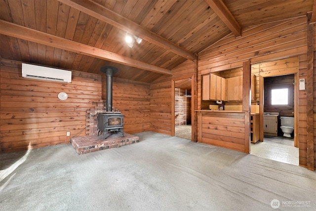 unfurnished living room with wooden walls, lofted ceiling with beams, a wall unit AC, carpet flooring, and a wood stove