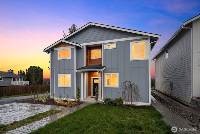 view of front of property featuring board and batten siding, a yard, and fence