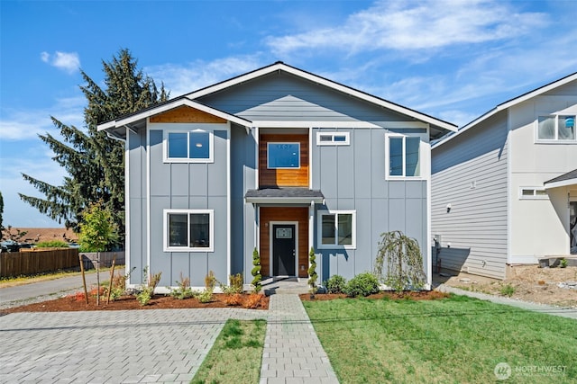 view of front of home with board and batten siding, a front lawn, and fence