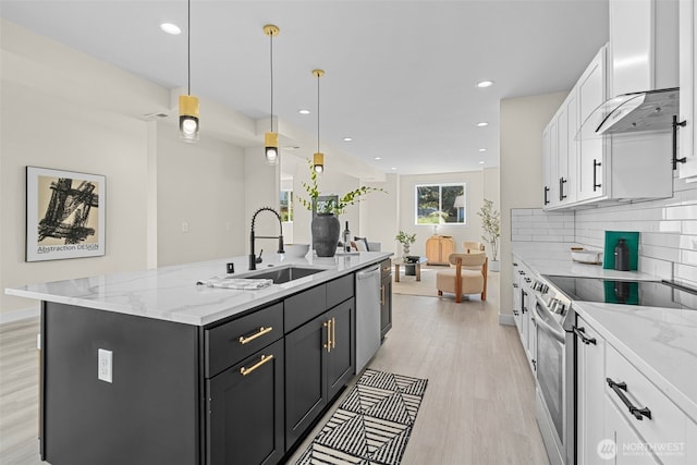 kitchen with an island with sink, a sink, appliances with stainless steel finishes, white cabinets, and extractor fan