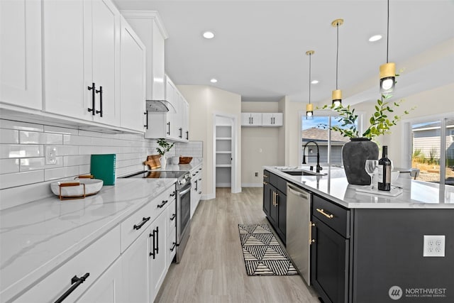 kitchen with an island with sink, a sink, backsplash, appliances with stainless steel finishes, and white cabinets