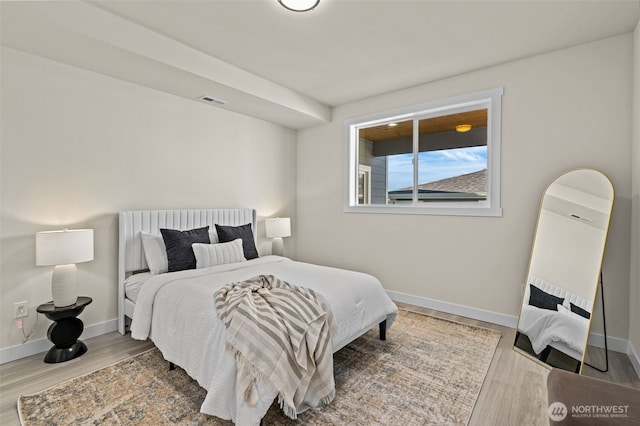 bedroom with wood finished floors, visible vents, and baseboards