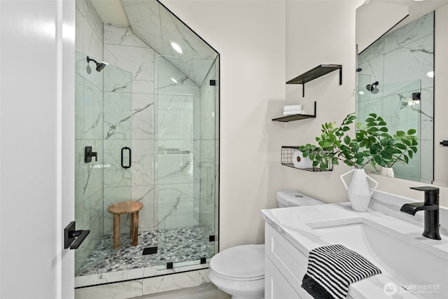 bathroom featuring marble finish floor, a stall shower, toilet, and vanity