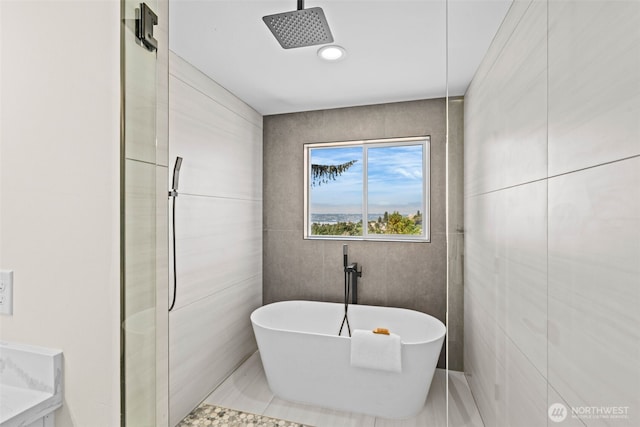 bathroom with a freestanding bath, tile walls, and walk in shower