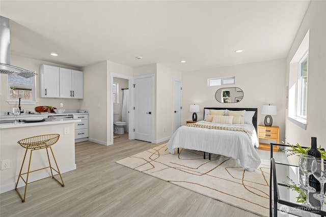 bedroom with ensuite bath, recessed lighting, light wood-style floors, and baseboards