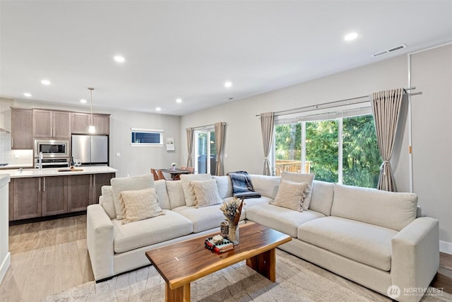 living area with recessed lighting, visible vents, and light wood-style flooring