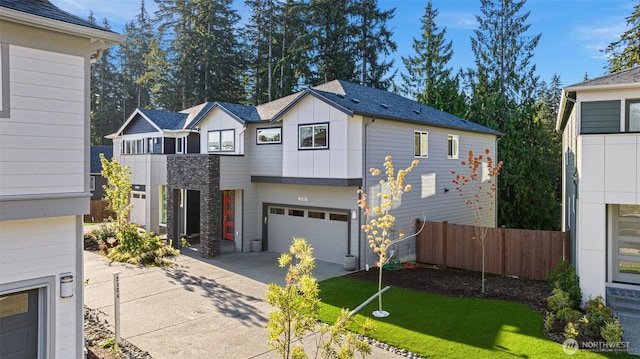 view of front of property with a garage, board and batten siding, driveway, and fence