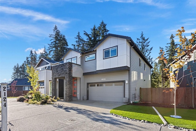 view of front of home with a garage, driveway, board and batten siding, and fence